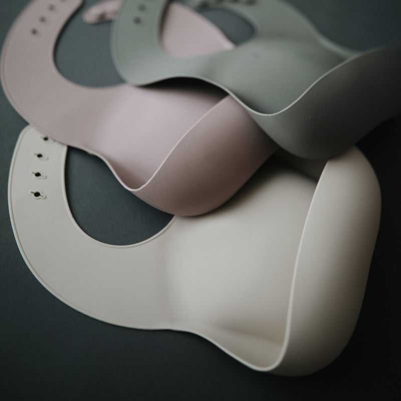 babete para bebés e crianças em silicone com bolsa colectora na cor shifting sand da marca mushie vista aproximada